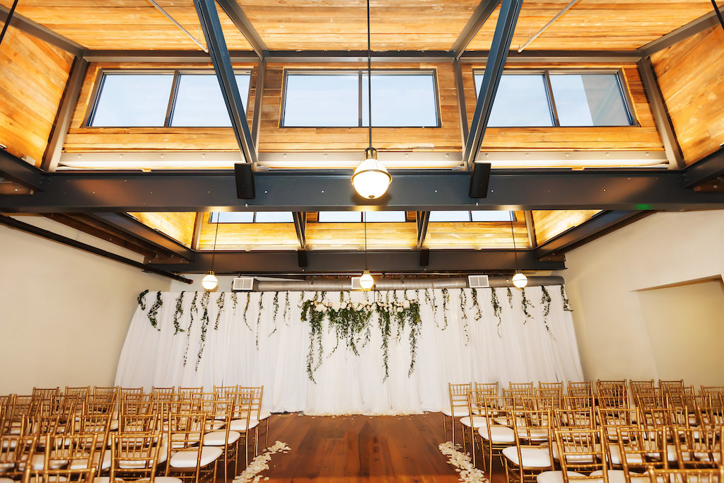 Indoor Industrial Chic Wedding Ceremony with White Draping, Greenery Ceremony Arch, Gold Chiavari Chairs and Rose Petal Aisle | Downtown Tampa Wedding Venue Oxford Exchange