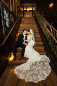 Interior Bride and Groom Portrait on Staircase, Bride with Long Floral Lace Veil, Groom in Navy Blue Tuxedo | Downtown Tampa Wedding Venue Oxford Exchange