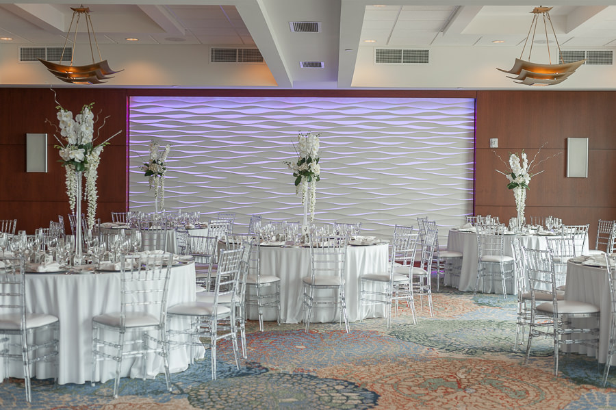 Elegant Modern, Hotel Ballroom Wedding Reception with Clear Chiavari Chairs, Round Tables, Silver Chargers, and Extra Tall Hanging White Floral with Greenery and Orchid Centerpiece | Tampa Bay Wedding Rental Company Kate Ryan Linen Rentals | Waterfront Venue Westin Tampa Bay