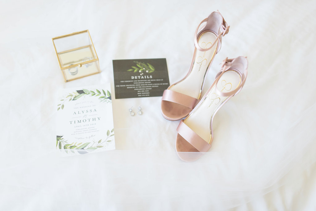 Blush Pink Ankle-Strap Sandal on White Tulle Background Greenery Inspired Invitation Suite Diamond Teardrop Earrings and Gold Clear Jewelry Box with Wedding Bands | Tampa Bay Wedding Photographer Kristen Marie Photography