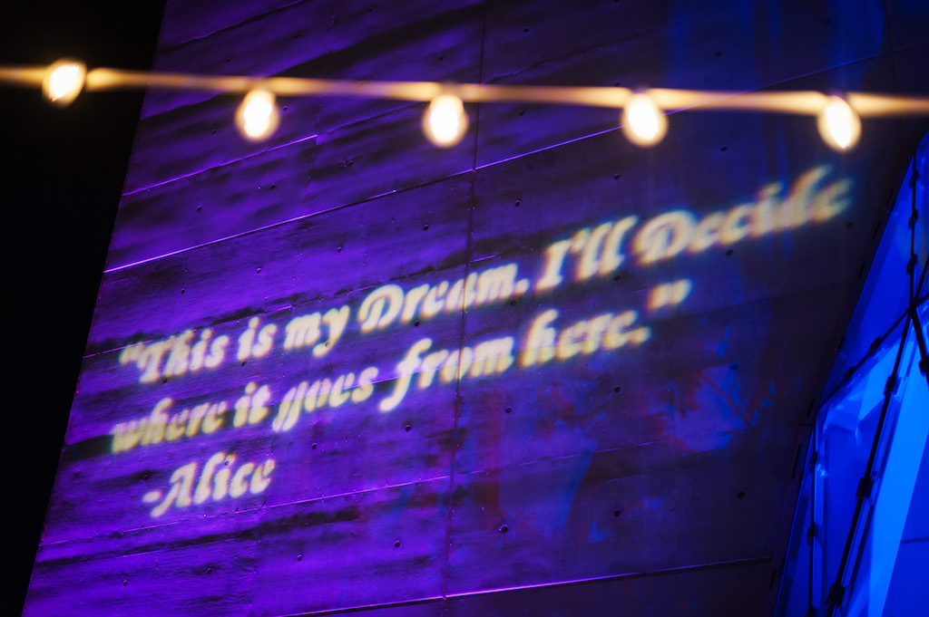 Alice in Wonderland Quote Projected on Wall with Blue and Purple Background and String of Bistro Lights