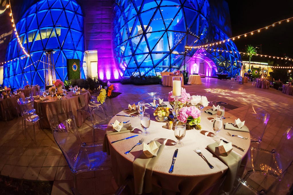 Salvador Dali Salvador Dali Museum Outside Reception Venue with Triangular Windows, Blue and Purple Uplighting, Reception Tables with Pink Flowers and Candles Centerpieces, Acrylic Clear Chairs and Hanging Bistro Lights Outside Reception Venue with Triangular Windows, Blue and Purple Uplighting, Reception Tables with Pink Flowers and Candles Centerpieces and Hanging Bistro Lights