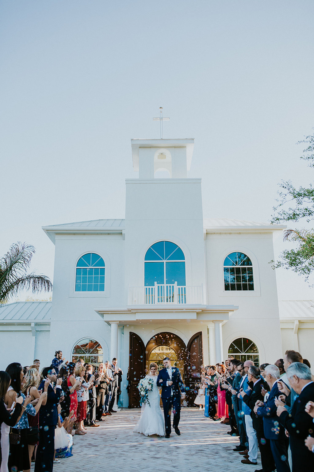 Outdoor Chapel Wedding Ceremony Bubble Exit Portrait, Bride in Stella York Wedding Dress with White Floral and Natural Greenery Bouquet, Groom in Navy Suit | Safety Harbor Wedding Venue Harborside Chapel