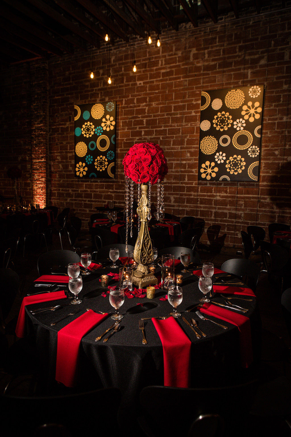 Great Gatsby Inspired Indoor Wedding Reception Decor Centerpiece at St. Pete Venue, Round Table with Black Satin Linens, Red Napkins, Red Roses Bouquets on Gold Vintage Pedestals with Hanging Crystals | Downtown St. Pete Wedding Venue NOVA 535