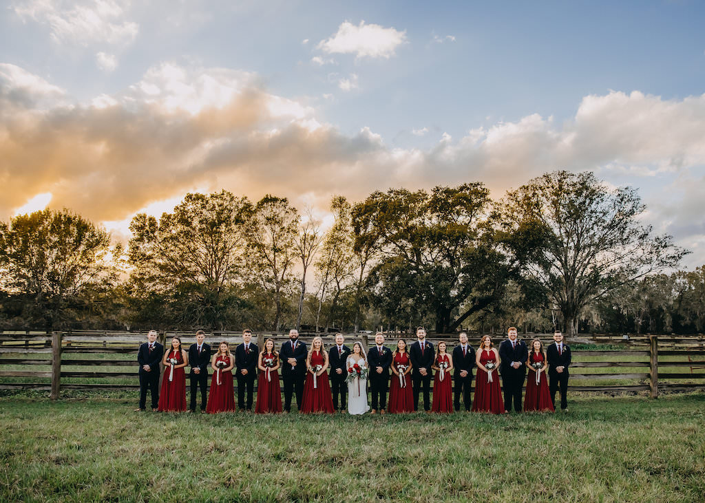 Outdoor Rustic Wedding Party Sunset Portrait, Groom and Groomsmen in Navy Suit and Red Ties, Bridesmaids in Matching Long Burgundy Red Dresses, Bride in Long Sleeve Lace Wedding Dress, Red, White and Greenery Bouquet |Tampa Bay Wedding Photographer Rad Red Creative | Lithia Rustic Wedding Venue Southern Grace