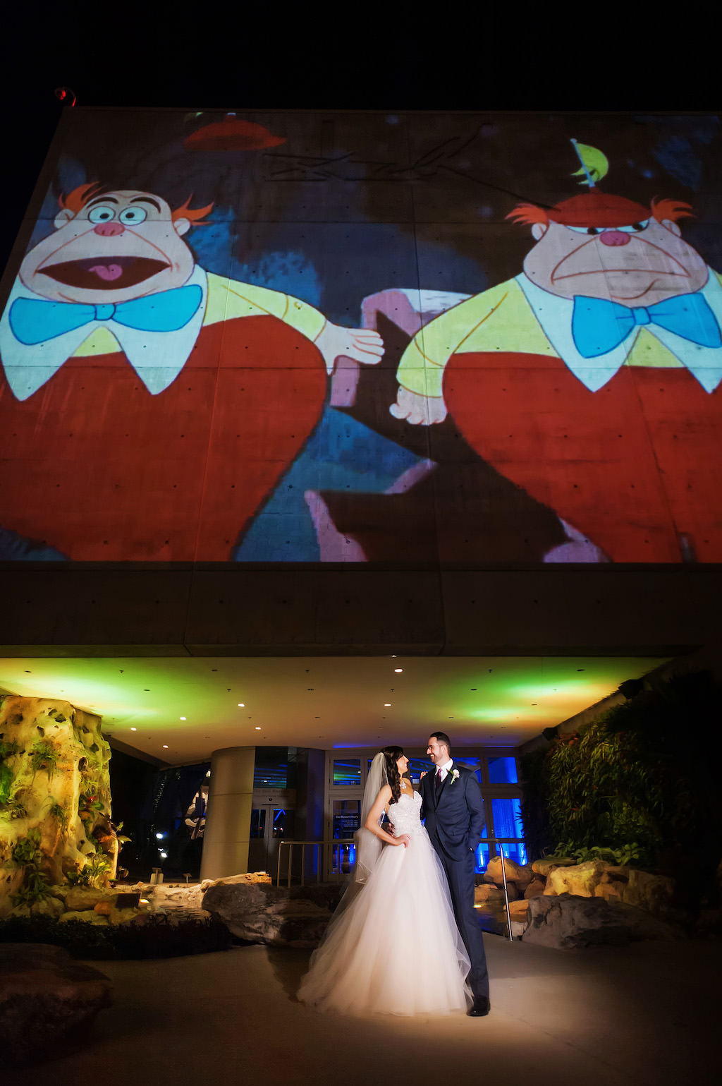 Bride and Groom Portrait Underneath Alice in Wonderland Tweedledee and Tweedledum Projected onto Dali Museum Building Outside
