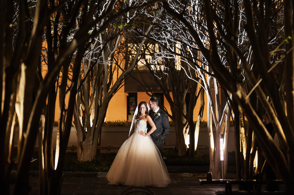 Bride and Groom Portrait Blush Pink Wedding Dress with Tulle Bottom Outside Dali Museum Venue Between Tree Branches Uplighted at Night | Tampa Bay Bridal Shop Truly Forever Bridal