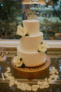 Three Tier Ivory Ruffled Buttercream Wedding Cake with White Roses and Gold Laser Cut Cake Topper on Vintage Gold Cake Stand and White Rose Petals