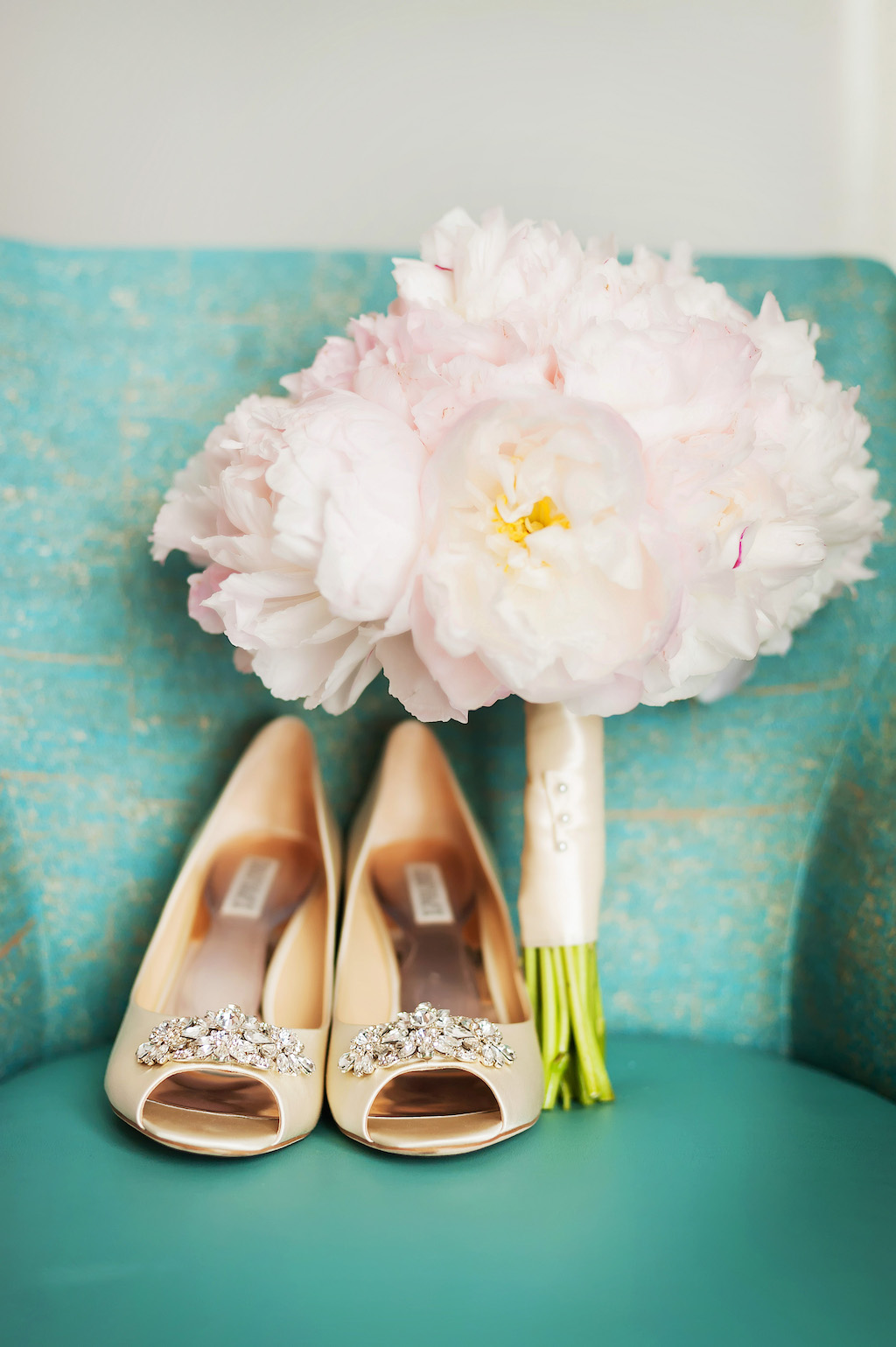 Bride's Gold Wedding Heels on Turquoise Couch with Blush Pink Peonies Bouquet Wrapped in Silk Ribbon