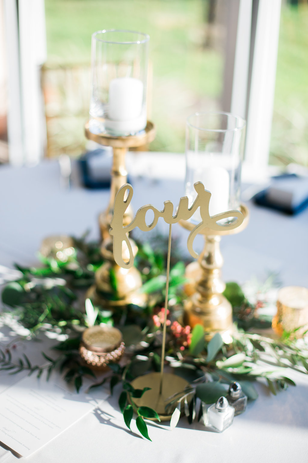 Indoor Vintage Wedding Reception with Greenery Centerpiece and Gold Pillar Candlestick Holders, White Linens and Gold Wooden Table Number | Naples Wedding Photographer Kera Photography