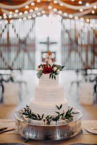 Rustic, Inspired Wedding Cake Three Tier White Ruffled Buttercream Wedding Cake with Red and White Floral with Greenery Topper and Bride and Groom Cake Topper on Silver Pedestal | Tampa Bay Wedding Photographer Rad Red Creative | Lithia Wedding Venue Southern Grace