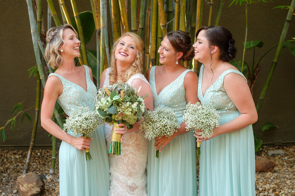 Outdoor Bridal Party Wedding Portrait, Bride in Fit and Flare Lace and Ruffle Skirt Wedding Dress with Tank Top Straps and Plunging V-Neckline, Bridesmaids in Matching Lace Bodice Bridesmaids Dresses with Greenery and White Floral Bouquet | St. Pete Photographer Marc Edwards Photography | Downtown St. Pete Wedding Venue NOVA 535