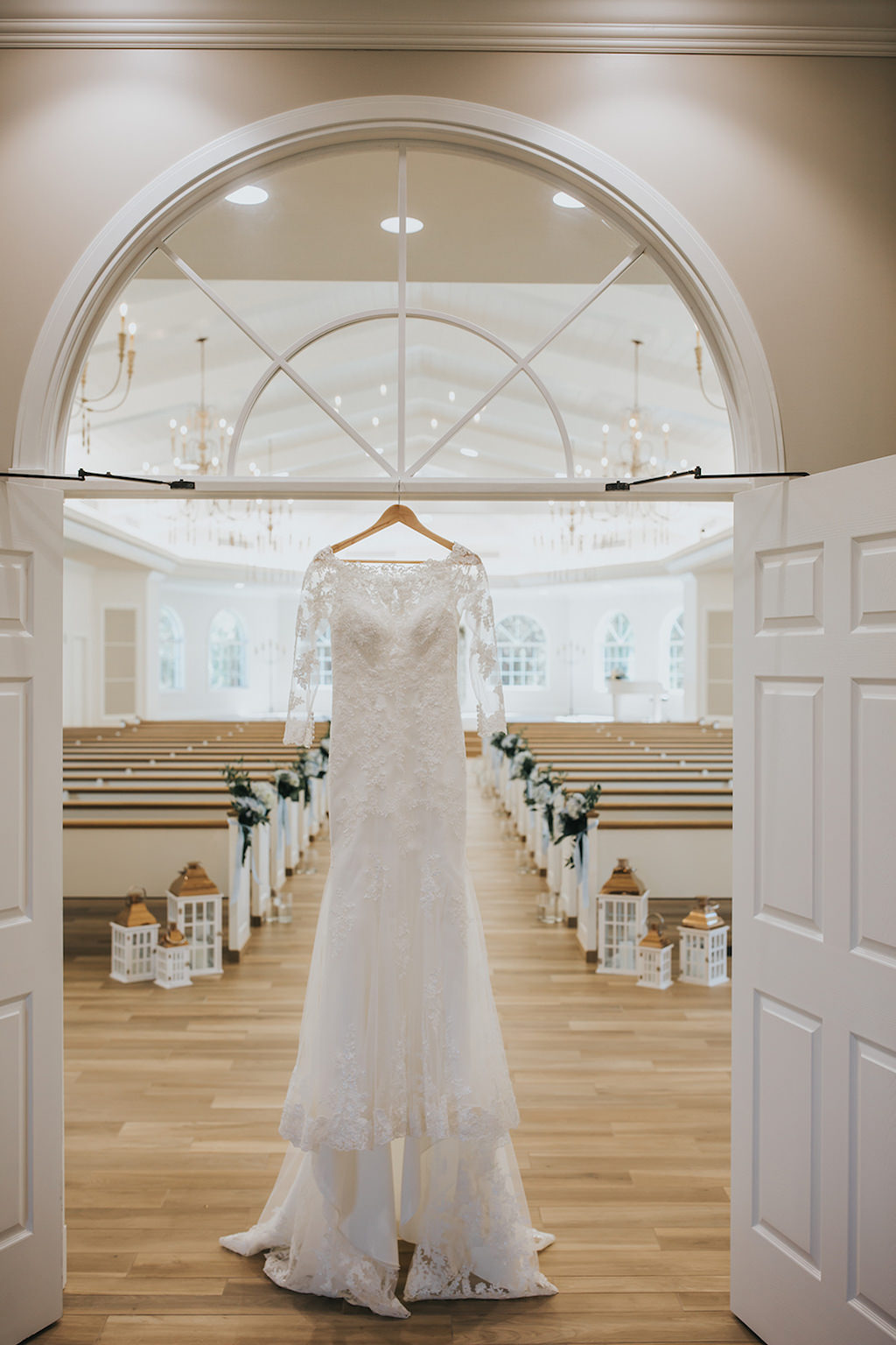 White Stella York Lace Wedding Dress with Long Sleeves Hanging on Wooden Hanger in Venue | Safety Harbor Wedding Ceremony Venue Harborside Chapel