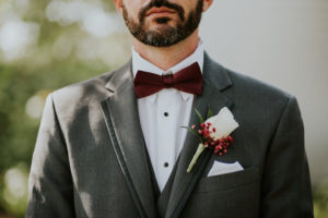 Groom Portrait in Grey Suit and Burgundy Bowtie with White Rose and Red Flower Boutonniere