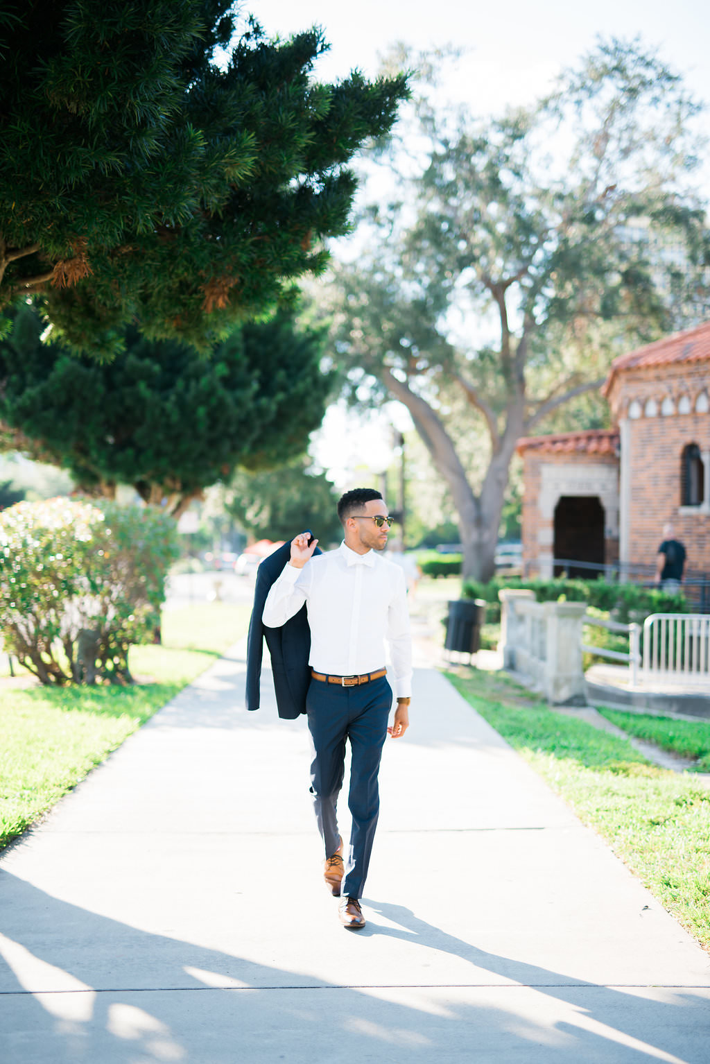 Outdoor Groom Portrait wearing White Suit Shirt and White Bowtie Holding Navy Blue Tuxedo Jacket | Downtown St. Pete Wedding Photographer Kera Photography