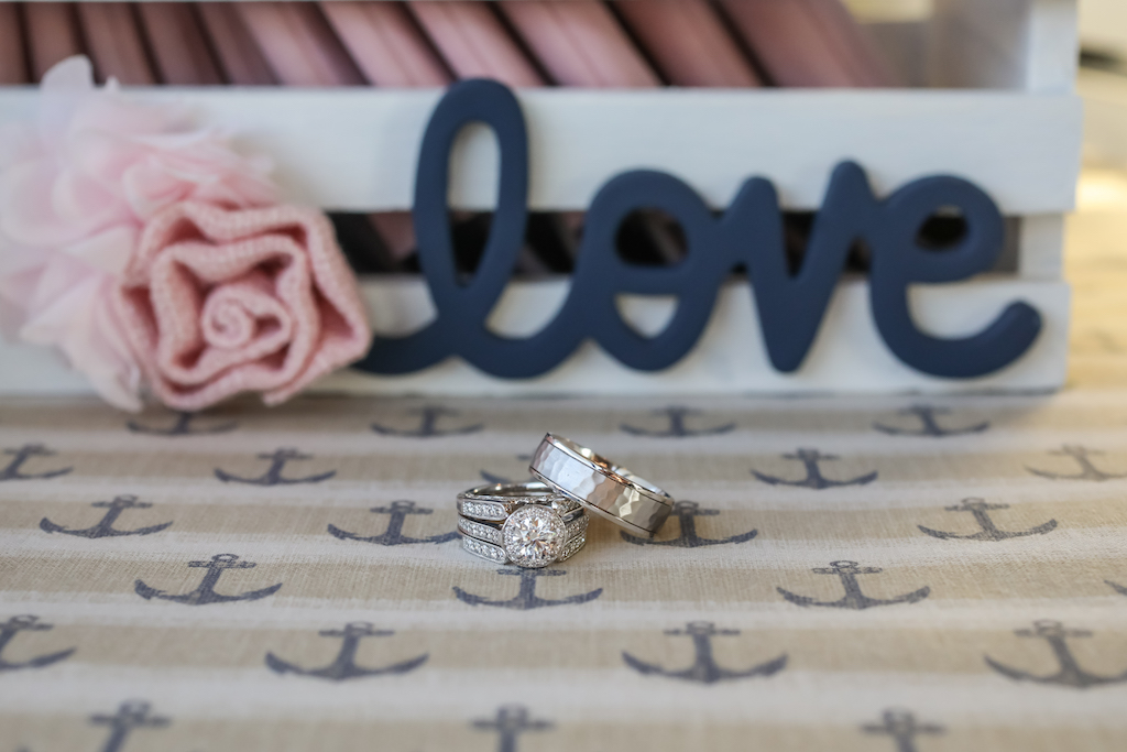 Double Band Diamond Wedding Ring, Round Engagement Ring with Diamond Halo, and Silver Men's Ring on Nautical Linen and Blue Wooden Love Sign | Tampa Bay Wedding Photographer Lifelong Photography Studio