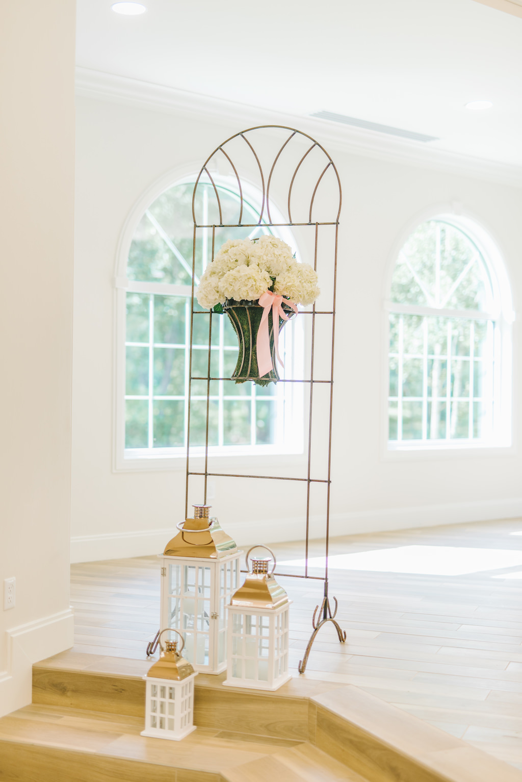 White Floral and Pink Ribbon Wedding Ceremony Decor on Metal Stand with White and Gold Lanterns | Safety Harbor Wedding Ceremony Venue Harborside Chapel | Clearwater Beach Photographer Kera Photography | Apple Blossoms Floral Designs