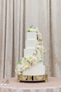 Five Tier White Ruffled Buttercream Wedding Cake with Cascading Blush Pink, Ivory Roses and Greenery on Gold Cake Stand and Blush Pink Satin Linen