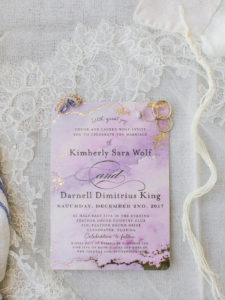 Purple Watercolor and Gold Foil Marble Wedding Invitation with Gold Engagement and Wedding Rings, Purple Diamond Earrings on White Lace