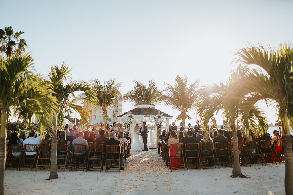 Outdoor Beach Wedding Ceremony Bride and Groom at Gazebo with Birchwood Arch, White Draping and White Florals | Waterfront Venue Isla Del Sol Yacht and Country Club