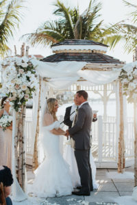 Outdoor Beach Wedding Ceremony Bride and Groom at Gazebo with Birchwood Arch, White Draping and White Florals | Waterfront Venue Isla Del Sol Yacht and Country Club