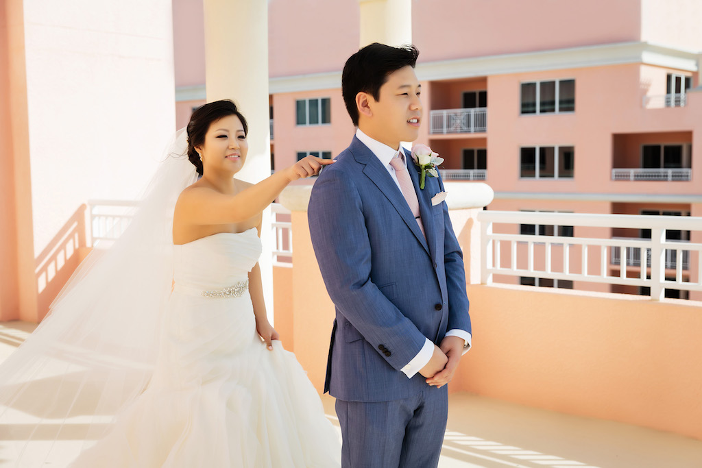 Outdoor Waterfront Hotel Rooftop Bride and Groom First Look Portrait, Bride in Strapless White Trumpet Organza Wedding Dress and Rhinestone Belt with Veil, Groom in Blue Suit with Blush Pink Tie and Blush and Ivory Rose Boutonniere | Venue Hyatt Regency Clearwater Beach