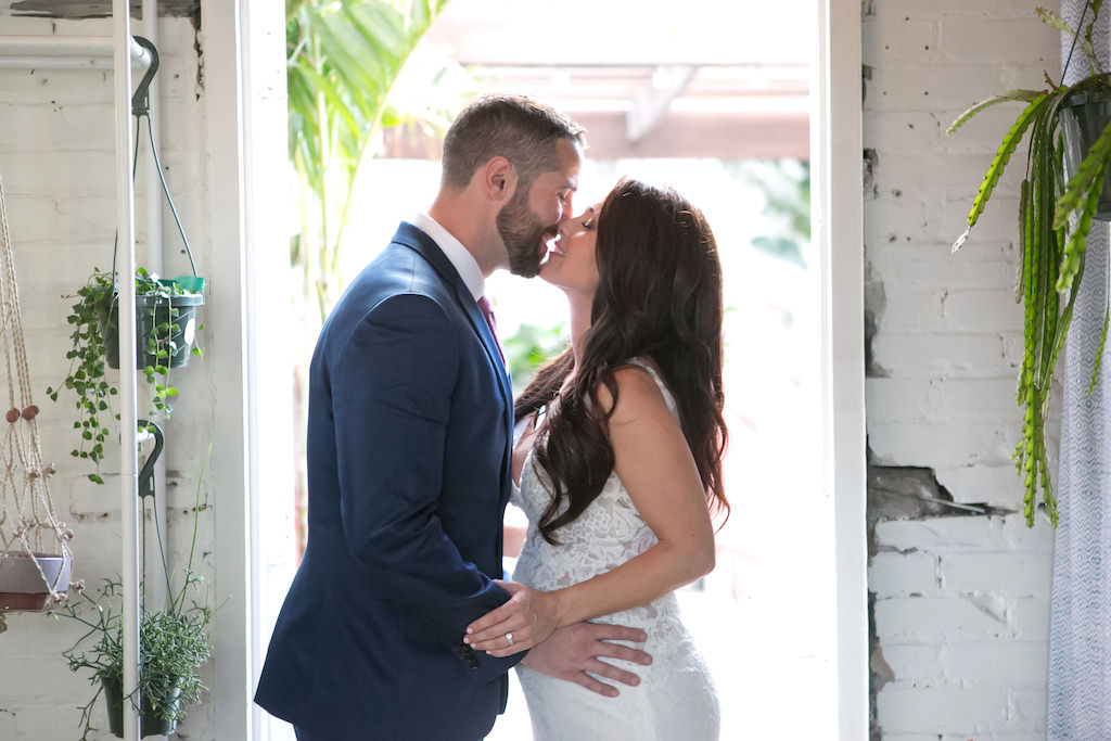 Indoor Bride and Groom Wedding Portrait, Bride Wearing V-Neck Lace Floor Length Wedding Dress, Curled Hair Down, Groom Wearing Navy Blue Suit and Red Tie | Tampa Bay Wedding Photographer Carrie Wildes Photography | Tampa Bay Wedding Venue Fancy Free Nursery