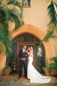 Outdoor Bride and Groom Portrait in V-neck Rhinestone Beaded Bodice and with Keyhole Back and Beaded Detailing Wedding Dress and Veil, Groom in Navy Blue Suit and Blush Pink Tie | Tampa Wedding Dress Shop Truly Forever Bridal