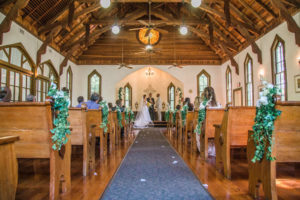 Dunedin Wedding Ceremony Venue Andrew's Memorial Chapel with Greenery and White Floral Ceremony and Pew Decor