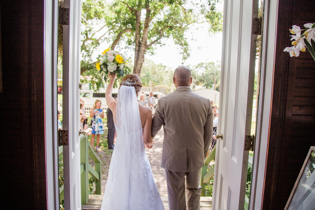 Outdoor Wedding Ceremony Exit Portrait at Tampa Bay Venue Andrews Memorial Chapel, Bride in Lace Strapless Wedding Dress and Veil with Yellow Sunflower, White Daisy and Greenery Floral Bouquet, Groom in Tan Suit