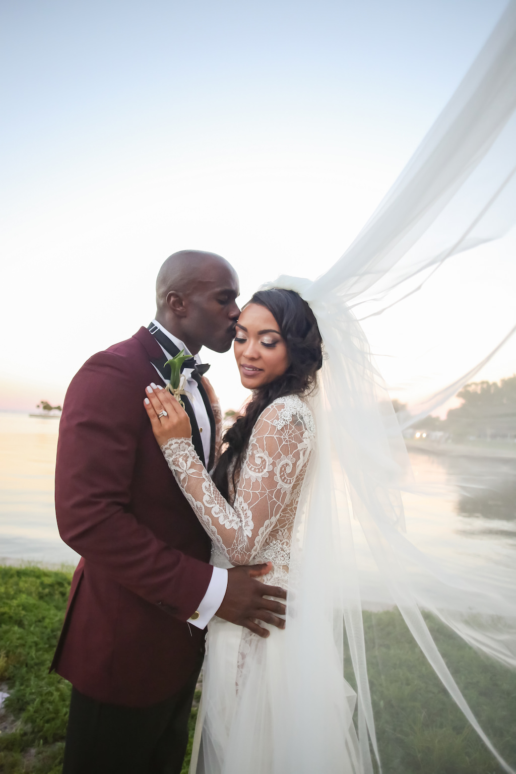Creative Outside Bride and Groom Wedding Portrait, Bride in Long Sleeve Lace Sheer High Neck Low Back Wedding Dress with Veil Blowing in the Wind, Groom in Dark Red Tuxedo | St. Petersburg Photographer Lifelong Photography Studios