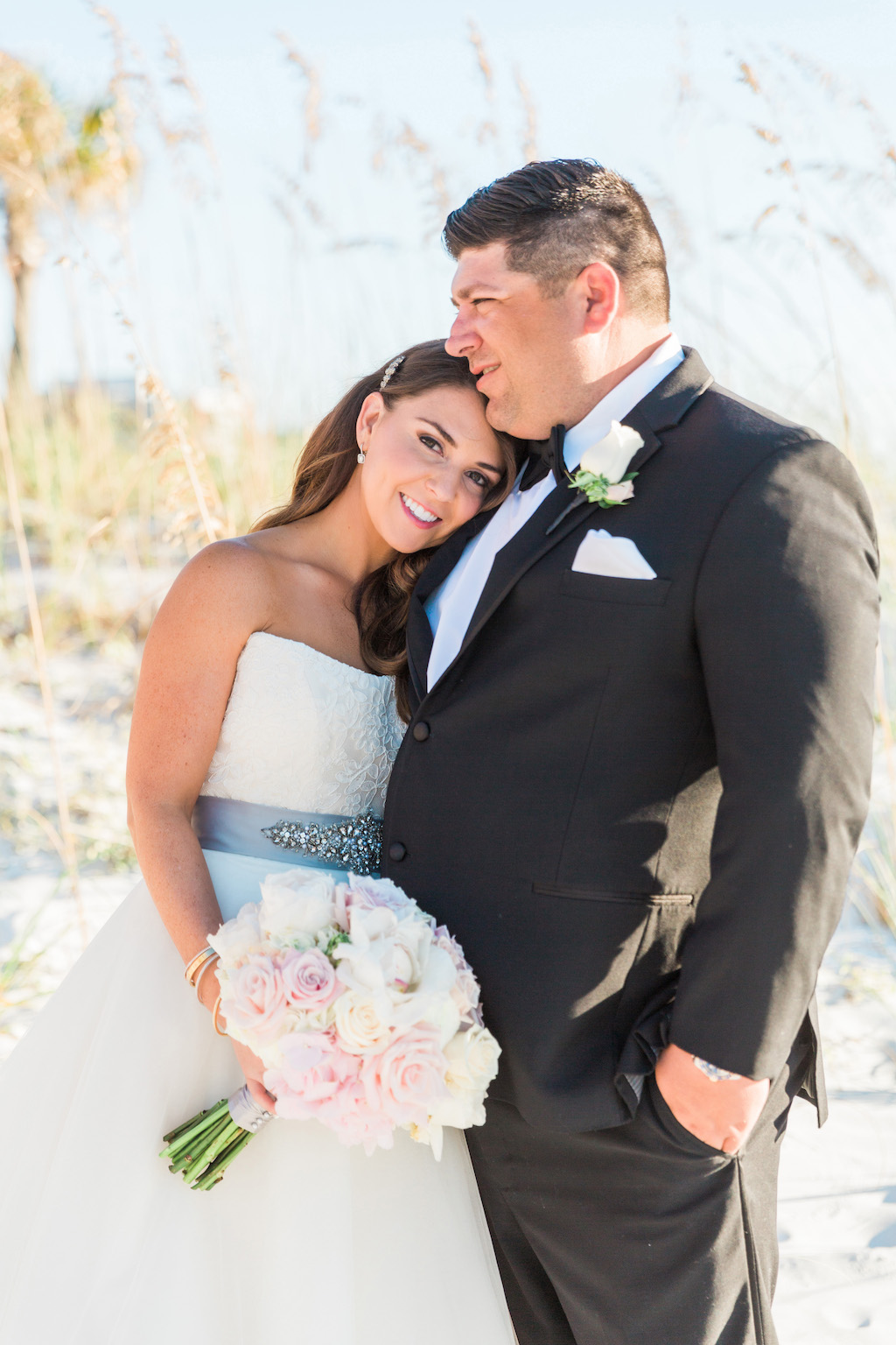 Outdoor Intimate Beach Bride and Groom Wedding Portrait in Ballgown Wedding Dress and Grey Sash with White and Pink Rose Bouquet, Groom in Black Tuxedo with White Floral Boutonniere