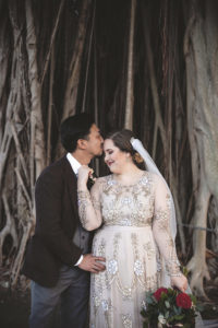 Outdoor Bride and Groom Wedding Portrait in Vintage Illusion Long Sleeve Cream Floral Beading Embellished Wedding Dress with Satin Belt and Fuchsia, Maroon, Blush Pink and Greenery Floral Bouquet, Groom in Black Tuxedo, Grey Vest, Colorful Bowtie and Blush Pink Rose Boutonniere | St. Petersburg Florist Cotton & Magnolia | Tampa Bay Hair and Makeup Femme Akoi