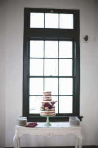 Old English Inspired Wedding Reception, Three Tier Semi Naked Wedding Cake with Maroon and Blush Pink Floral Accent on Turquoise Cake Stand on Antique White Table