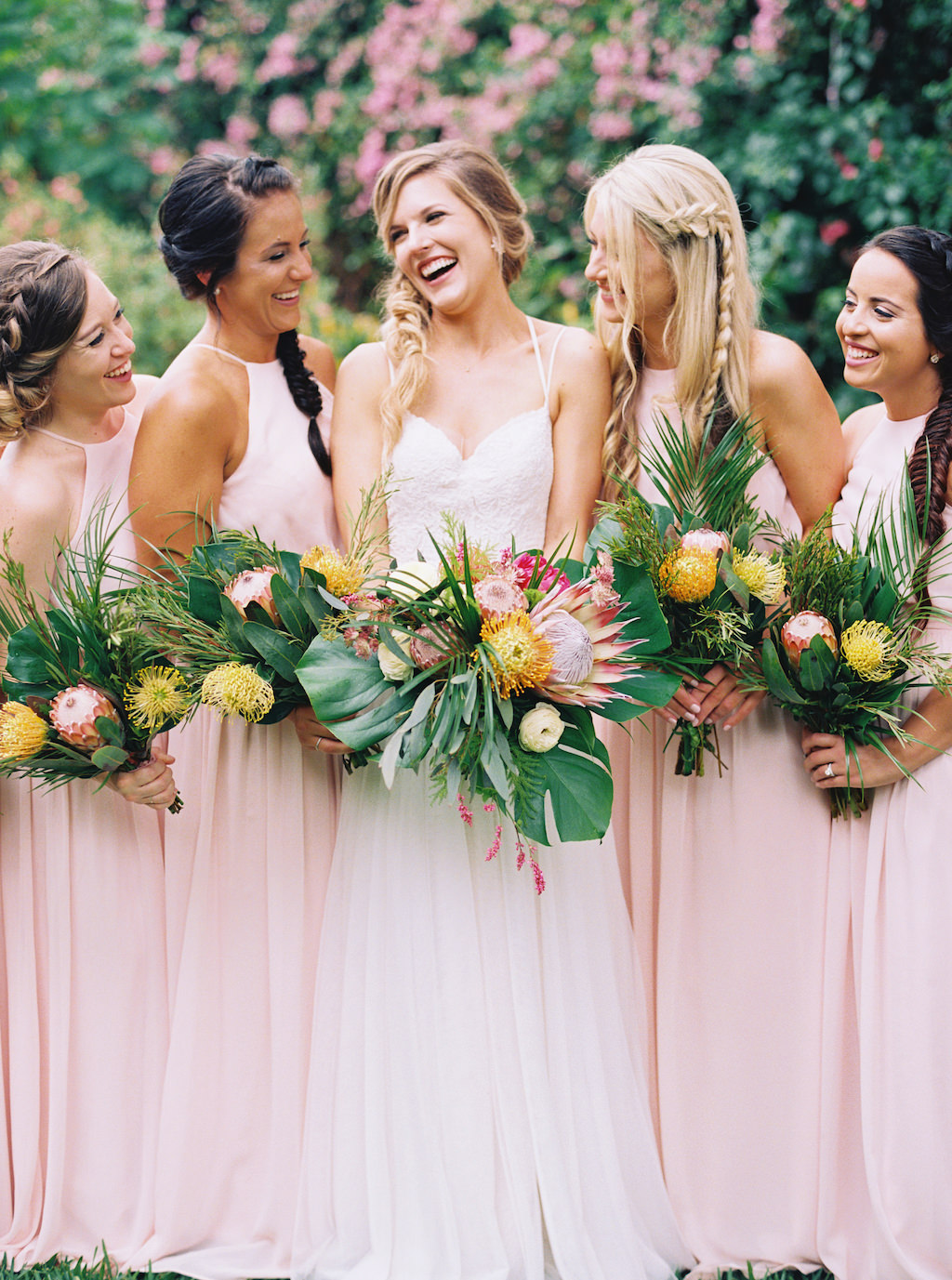 Outdoor Bride and Bridesmaid Portrait in Long Blush Pink Matching Dresses, Bride in Strappy V-neck Lace Wedding Dress with Tropical Pink, Yellow and Greenery Bouquets | St. Pete Wedding Planner Southern Glam Events and Weddings