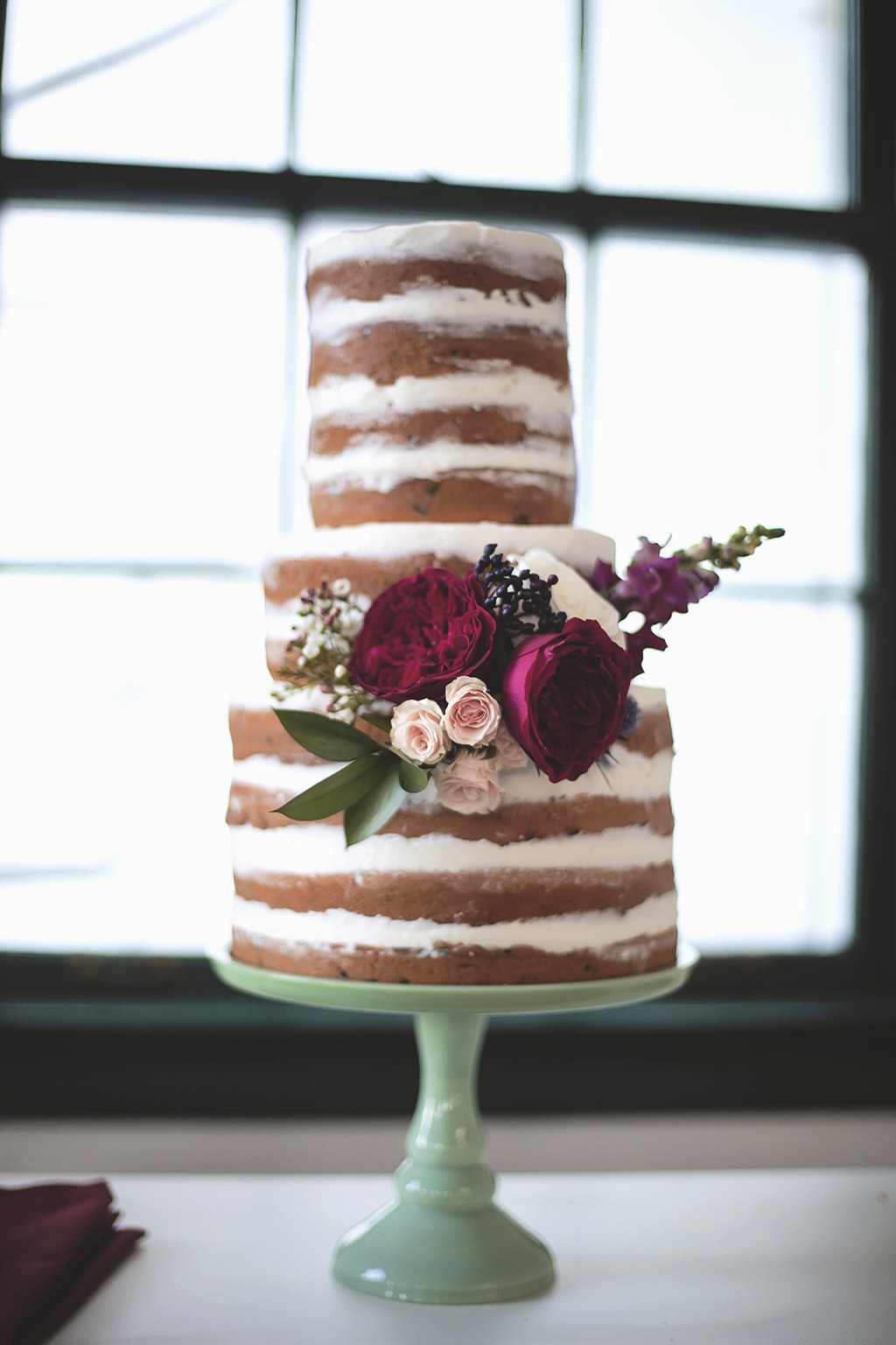 Three Tier Semi Naked Wedding Cake with Maroon and Blush Pink Floral Accent on Turquoise Cake Stand