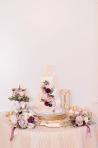 Three Tier Ivory-White and Mauve Marble Wedding Cake with Dark Red, Lilac, Blush Pink and Greenery Real Flowers, Laser Cut Gold Cake Topper, Purple/Lilac White Rose and Maroon Flower Bouquets on Ivory Tablecloth | Tampa Bay Wedding Planner Burlap to Lace