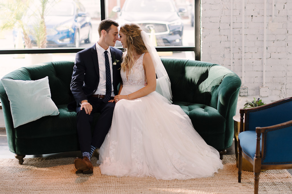 Bride and Groom Wedding Portrait on Vintage Green Velvet Couch, Groom in Navy Blue Suit, Bride in White A-Line Illusion Tank Top Strap Plunging V-Neckline Lace and Beaded Bodice Wedding Dress, Braided Half Up-Do and Veil | Tampa Bay Rentals A Chair Affair
