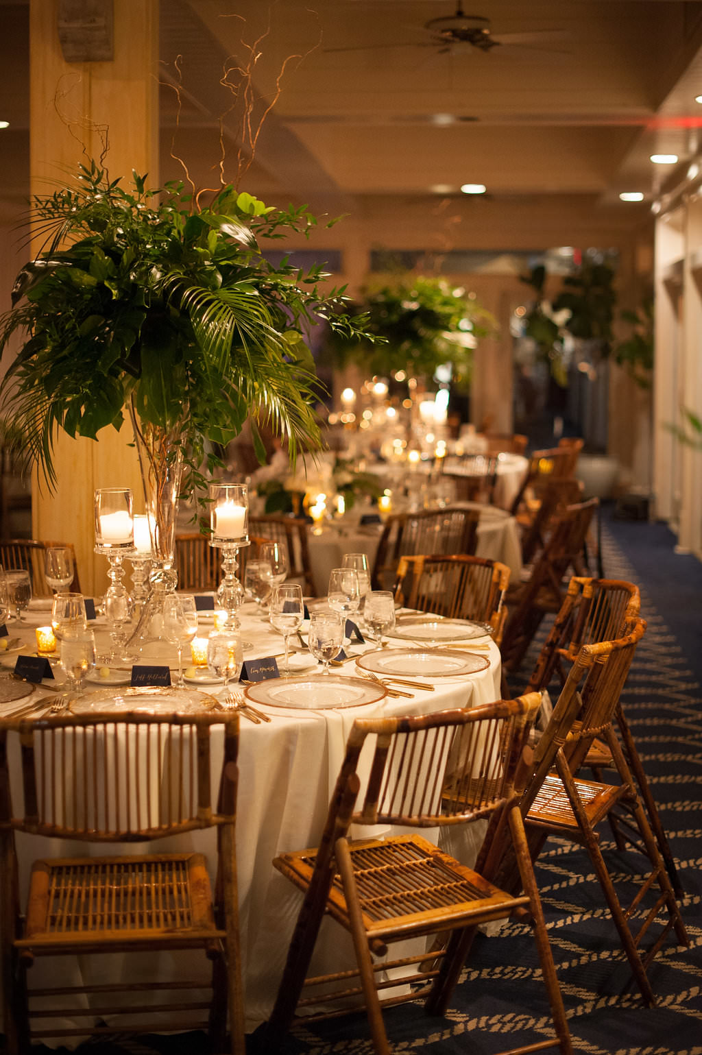 Indoor Wedding Reception Decor, Tall Glass Cylinder Vase with Tropical Green Leaves and Wooden Brown Chairs | Tampa Wedding Planner Parties A La Carte | Clearwater Beach Wedding Venue Carlouel Yacht Club | St Pete Rentals Over The Top Linen Rentals and A Chair Affair