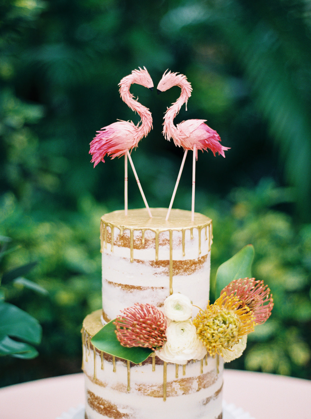 Round Two Tier Semi Naked Wedding Cake and Gold Drip Detailing with Fresh Tropical Flowers, Pink Flamingo Cake Topper