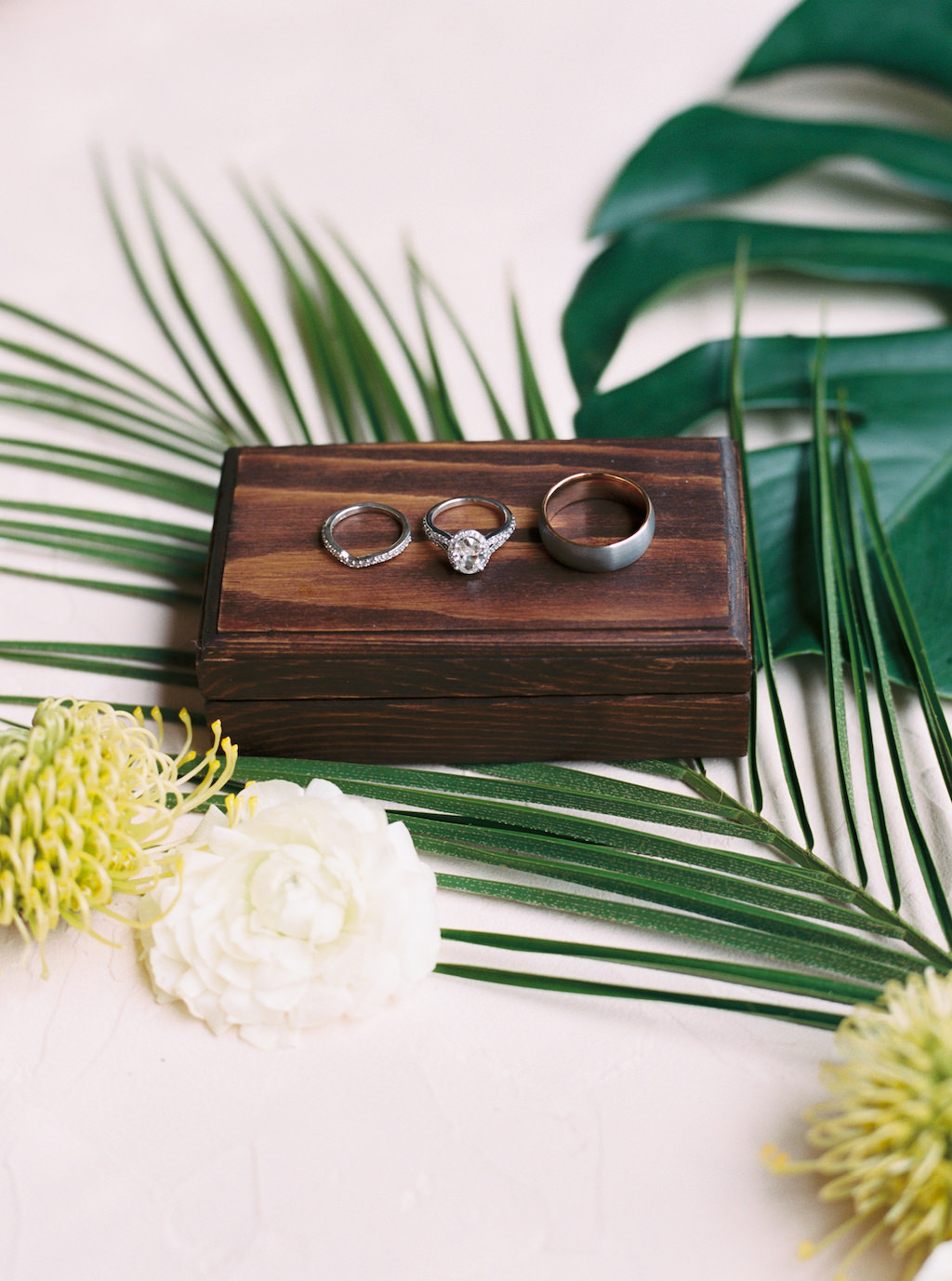 Wedding Rings on Wooden Box and Palm Tree Leaves
