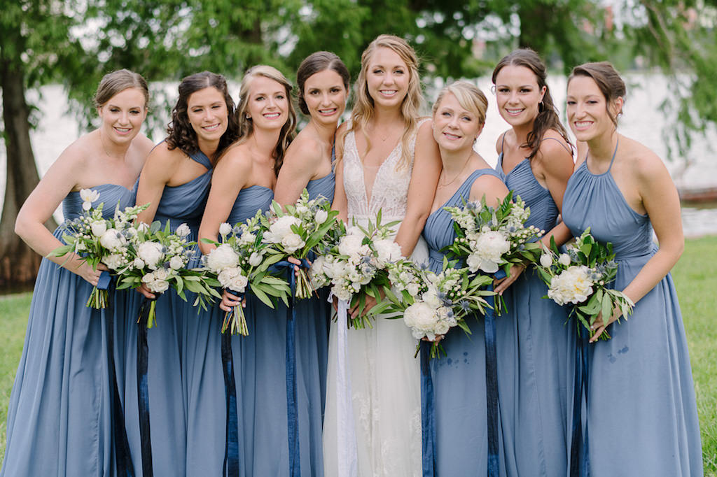 Outdoor Bridal Party Portrait, Bride in Plunging V Neck Illusion Lace A Line Wedding Dress, Bridesmaids in Dusty Blue Tank Top Dresses and White and Greenery Floral Bouquets