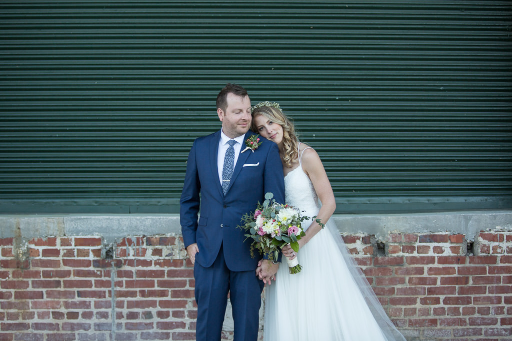 Outdoor Bride Wedding Portrait in A-line Strappy Lace and Tulle Wedding Dress with Greenery, White and Pink Floral Bouquet, Curled Hair Down and Veil, Groom in Navy Blue Suit and Greenery Boutonniere | Tampa Bay Hair and Makeup Femme Akoi Beauty Studio
