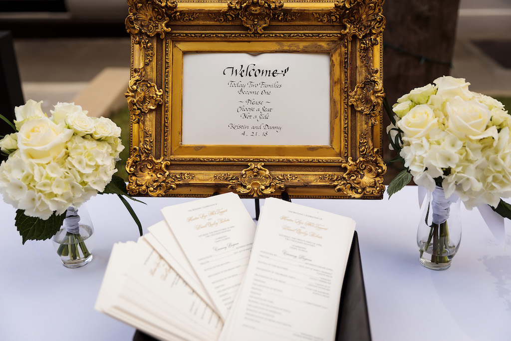 Wedding Ceremony Decor Welcome Table with Sign in Vintage Gold Frame, Two Glass Vases with White Hydrangeas and White Roses and Wedding Programs