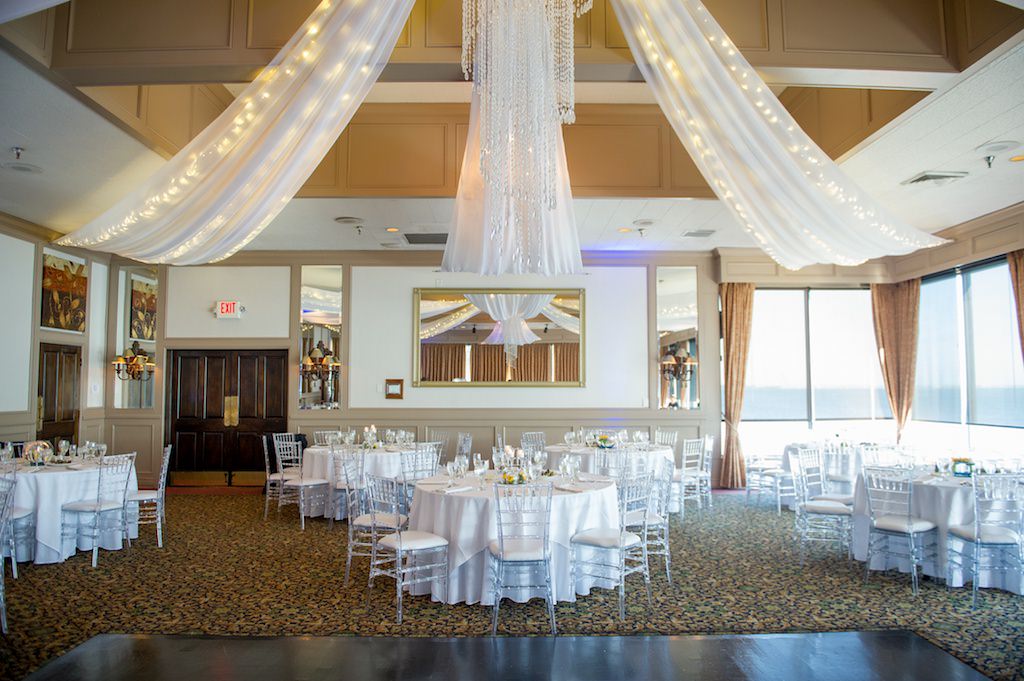 Ballroom Wedding Reception Decor, Round Tables, White Tablecloths, Clear Acrylic Chiavari Chairs, Crystal Chandelier, Draping and String Lights | Tampa Bay Photographer Andi Diamond Photography | Tampa Venue Rusty Pelican