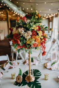 Tropical Inspired Wedding Ceremony Decor, Tall Centerpiece with White, Orange, Yellow, Red, and Greenery Florals on Golden Candlestick and Palm Tree Leaves | Tampa Bay Photographer Rad Red Creative