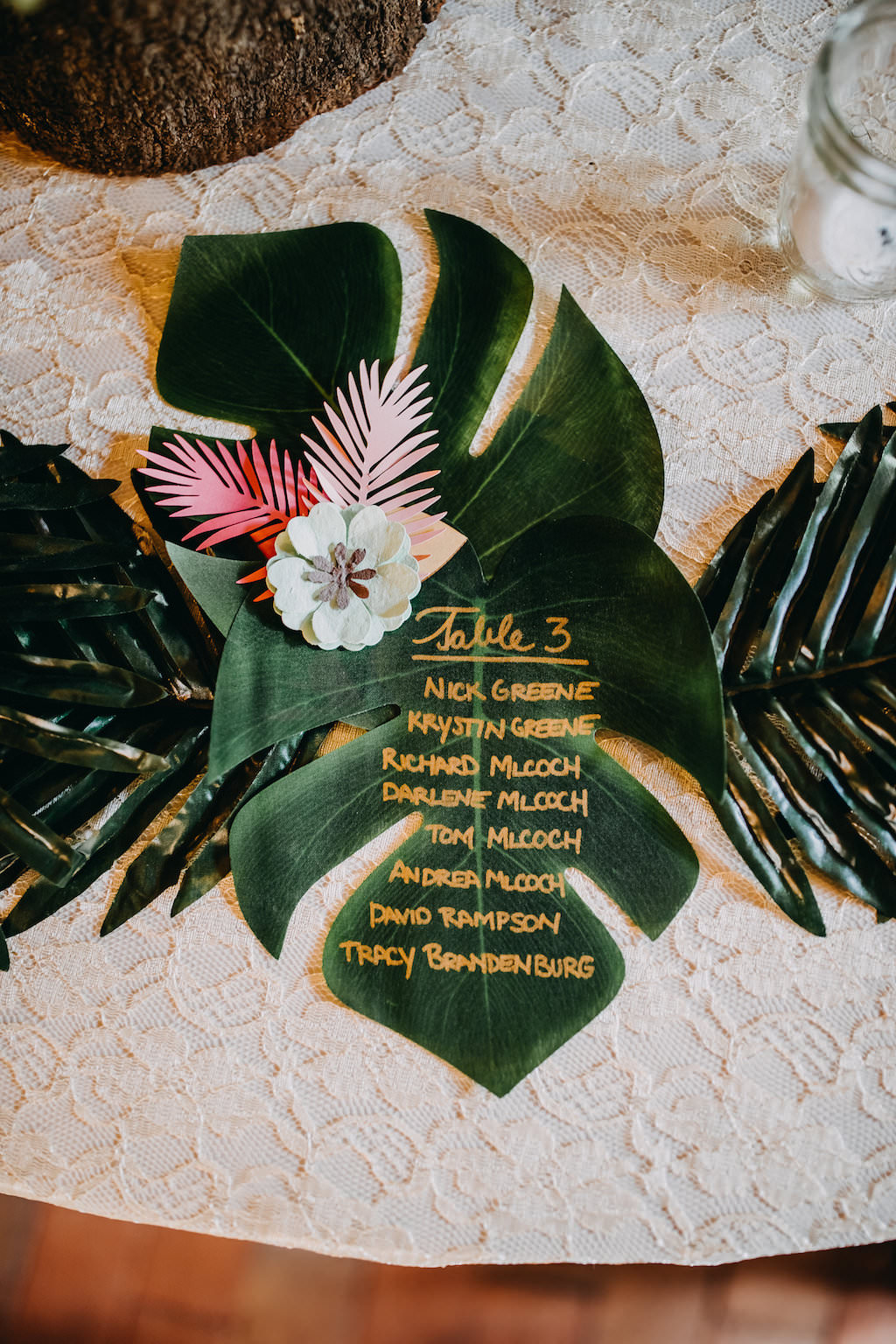 Unique Creative Tropical Inspired Table Seating on Palm Fronds with Gold Font and White and Pink Paper Flower | Tampa Bay Photographer Rad Red Creative