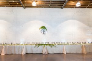 Wedding Reception Decor, Long Feasting Table with Gold Tablecloth and Greenery, Chiavari Chairs and Laser Cut Initial Hanging on Wall with Greenery Bouquet | Tampa Bay Photographer Andi Diamond Photography | Rentals A Chair Affair | Modern Lakeland Venue Haus 820