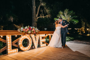Outdoor Nighttime Bride and Groom Portrait with LOVE Sign and Tropical Floral Bouquet | Tampa Bay Photographer Rad Red Creative