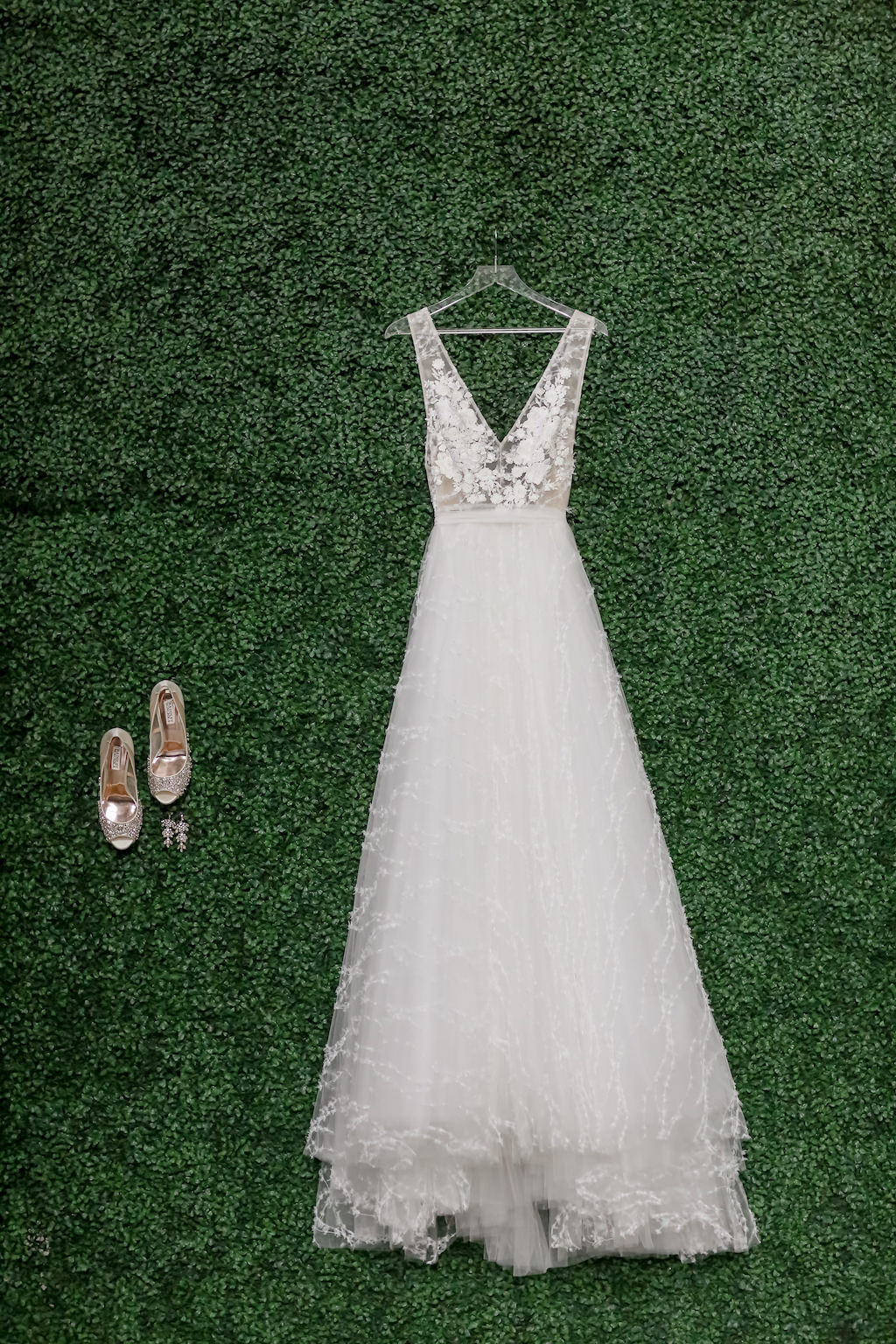 A-Line Illusion Plunging V-Neck Neckline with Tank Top Straps and Floral Lace Appliques Wedding Dress Hanging on Greenery Wall, Wedding Shoes and Earrings | Tampa Bay Photographer Lifelong Photography Studios | Dress Shop The Bride Tampa | Downtown St. Pete Wedding Venue The Birchwood